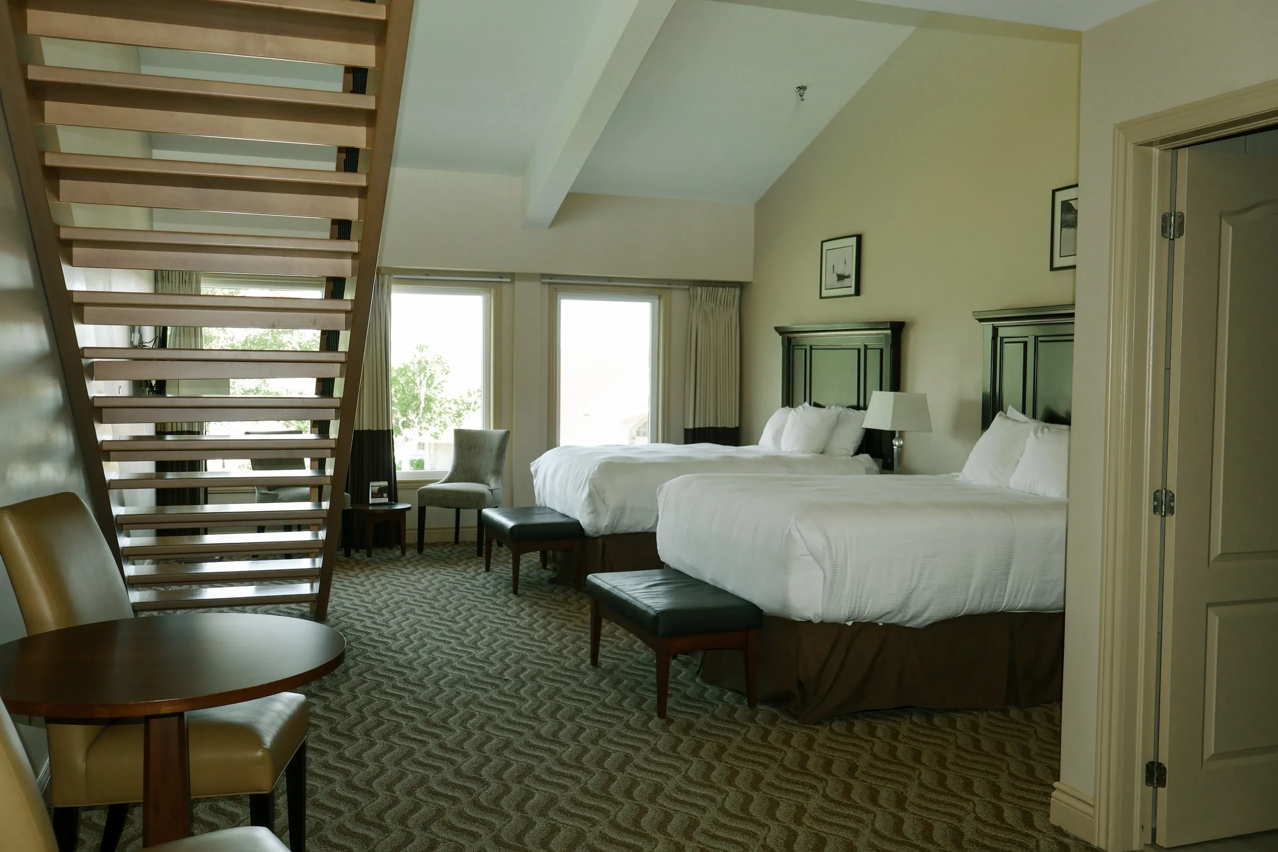 A guest room with two beds and an open wooden stair screen along the left wall.