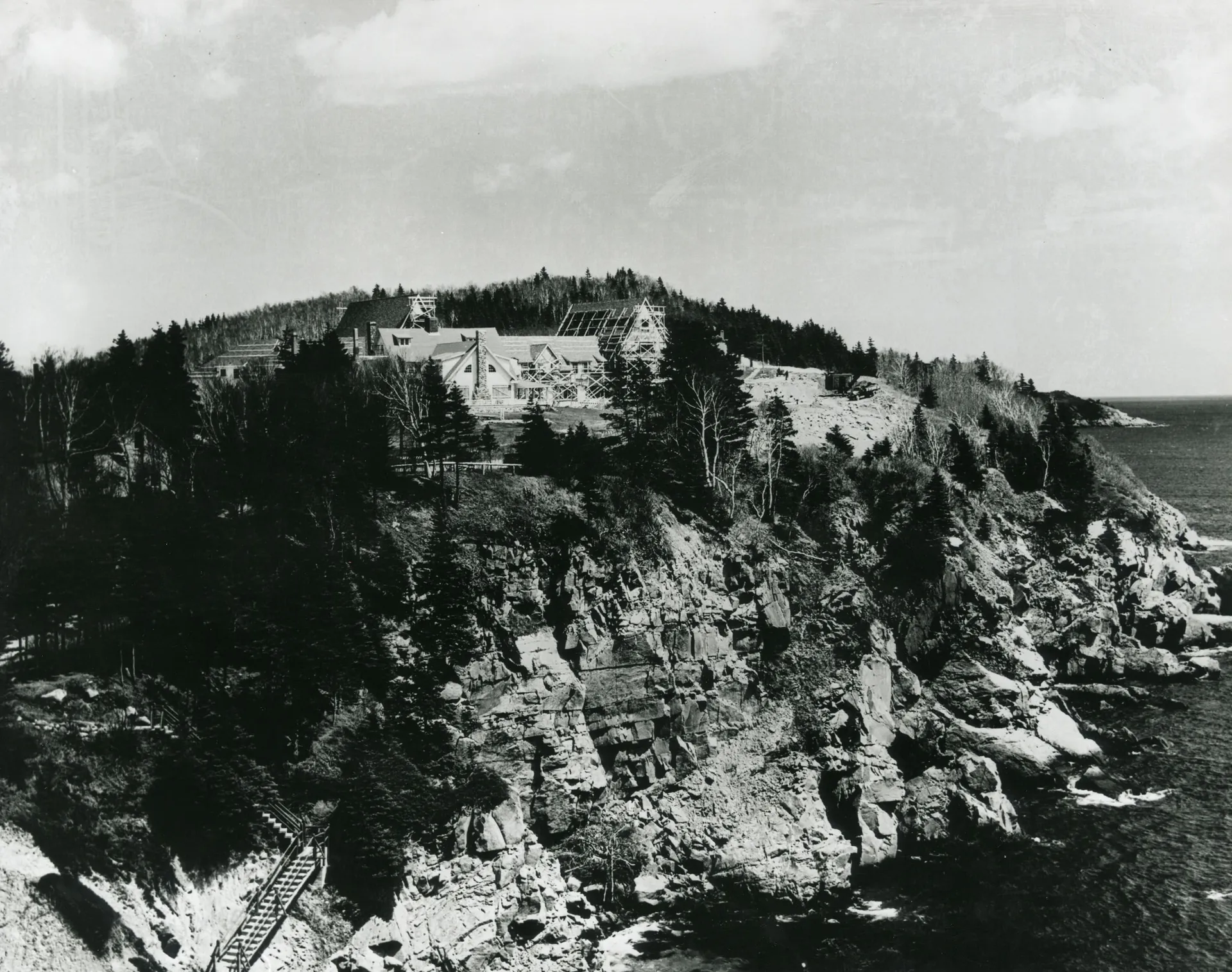 Buildings perched on a rocky coastline in a grainy black-and-white archival photograph.