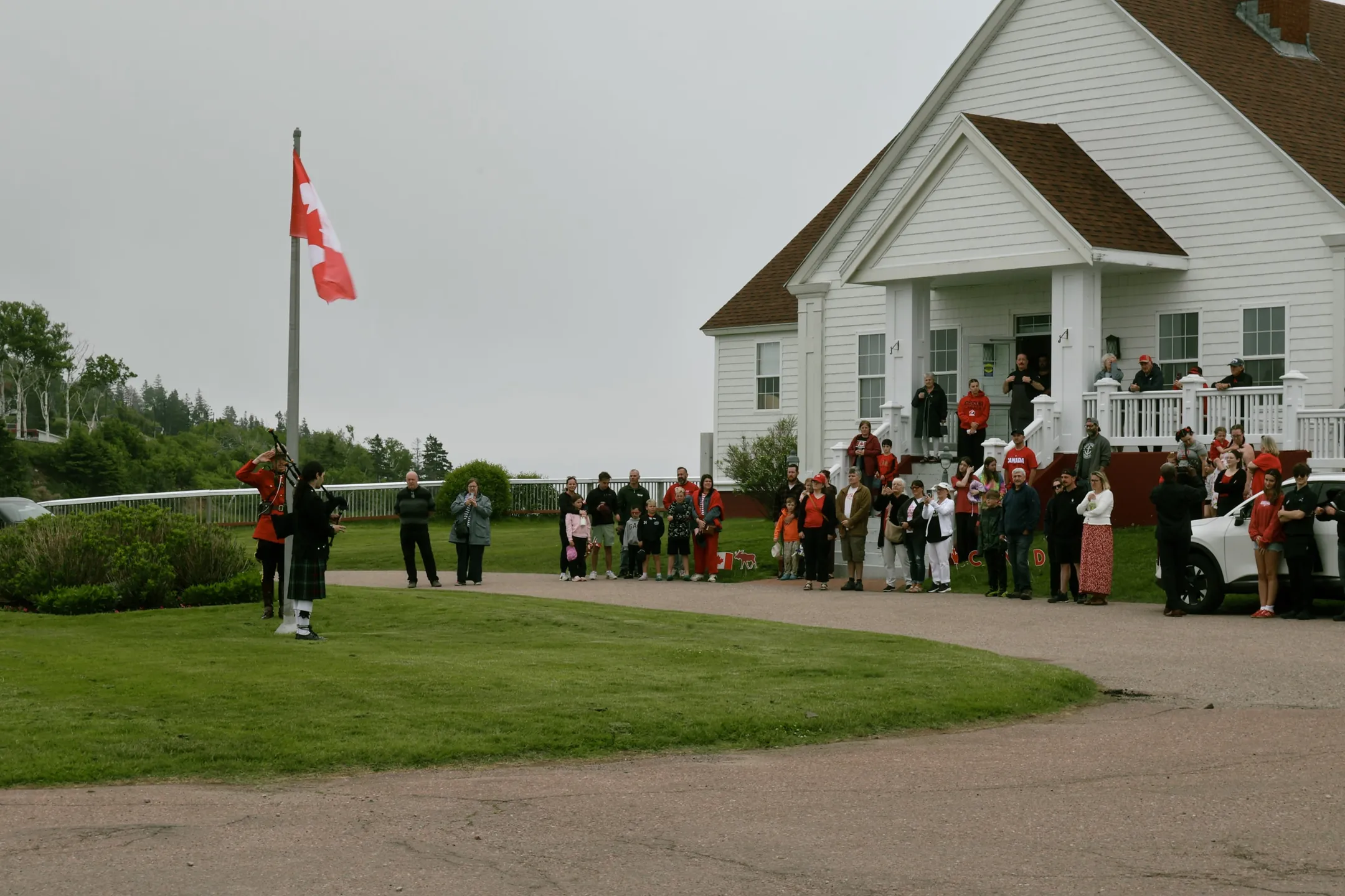 A Canada Day gathering with a Canadian flag outside a white lodge