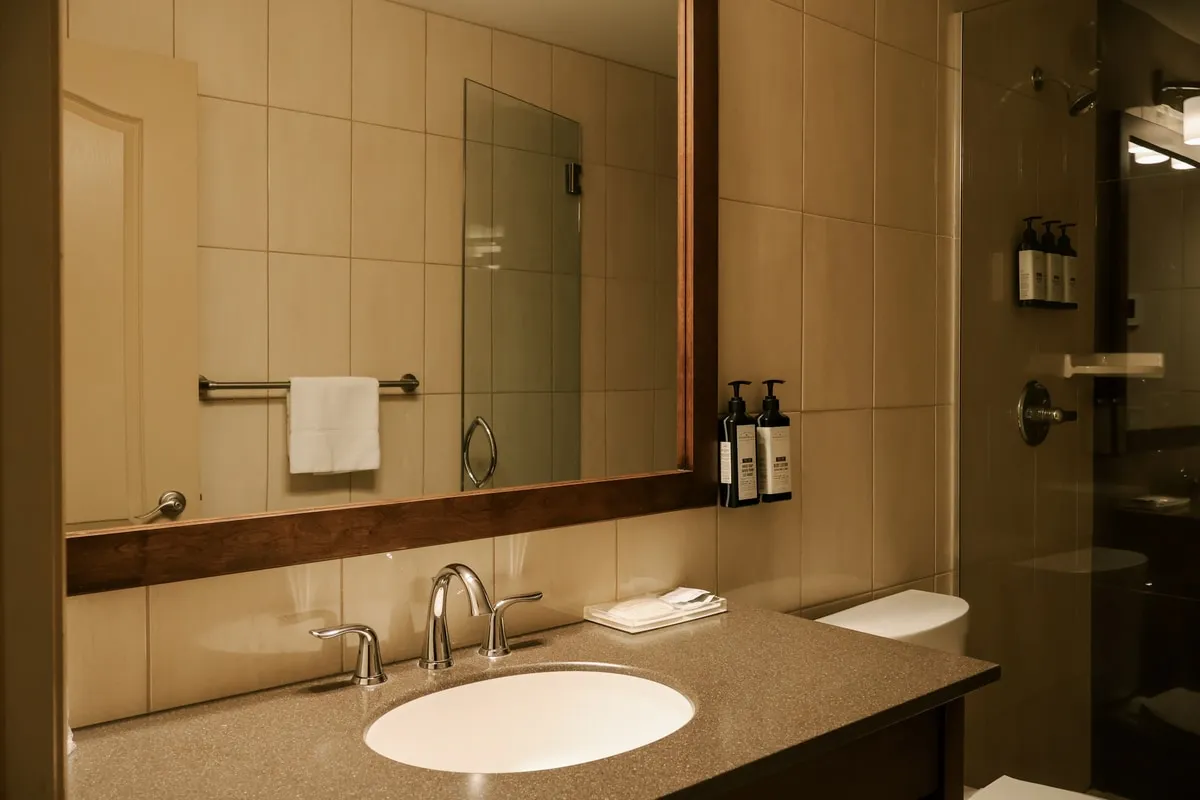 A bathroom with a wood-framed mirror, an oval sink, and a glass shower.