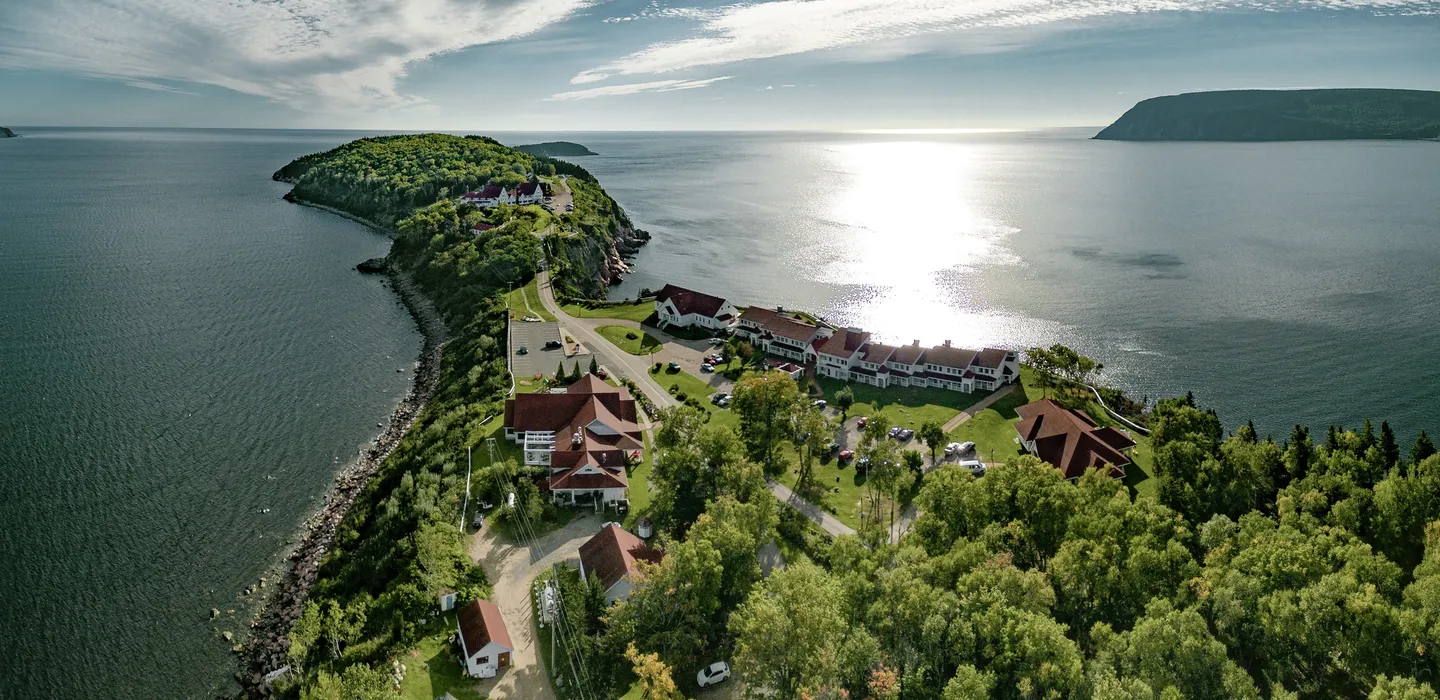 Aerial view of The Keltic Resort on Middle Head peninsula, with white buildings and red roofs along the Atlantic shore