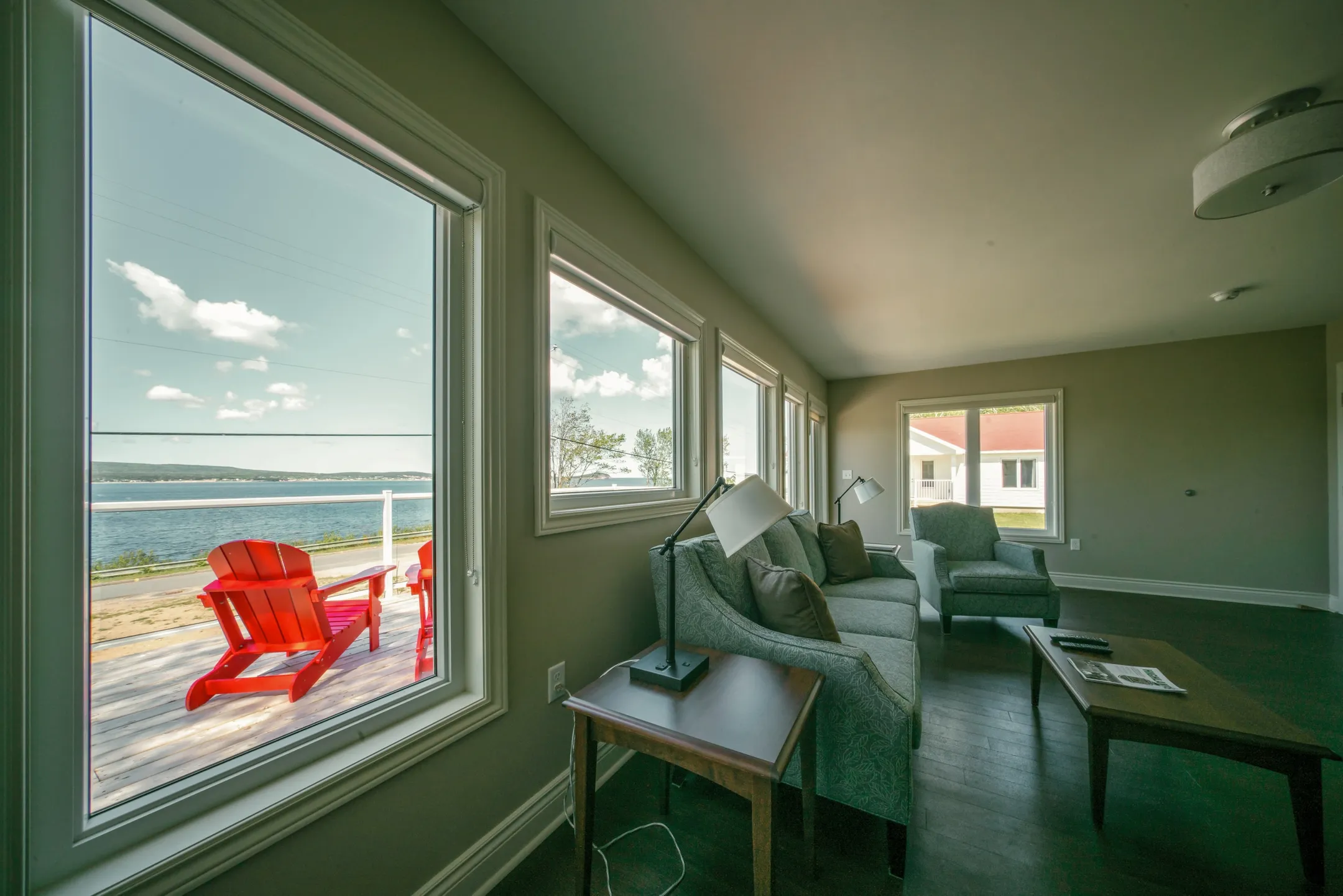 A living area corner with a side table, lamp, and window looking toward the coast.