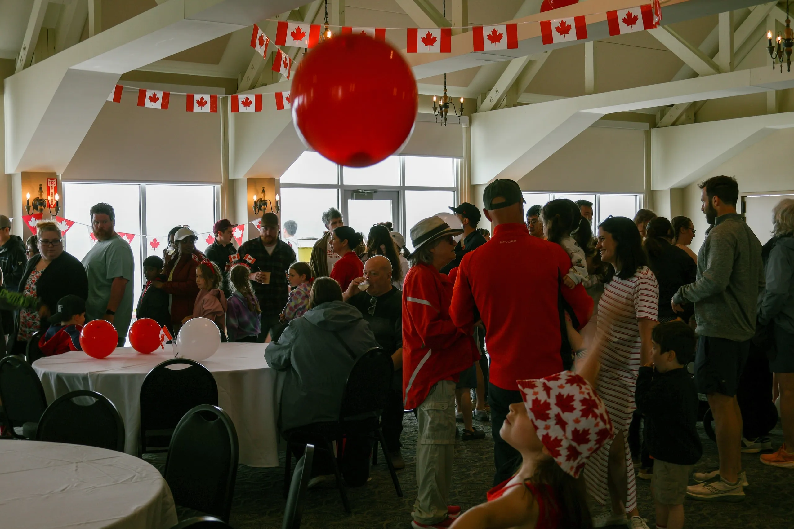 Guests celebrating Canada Day in the lodge under maple-leaf bunting and red balloons