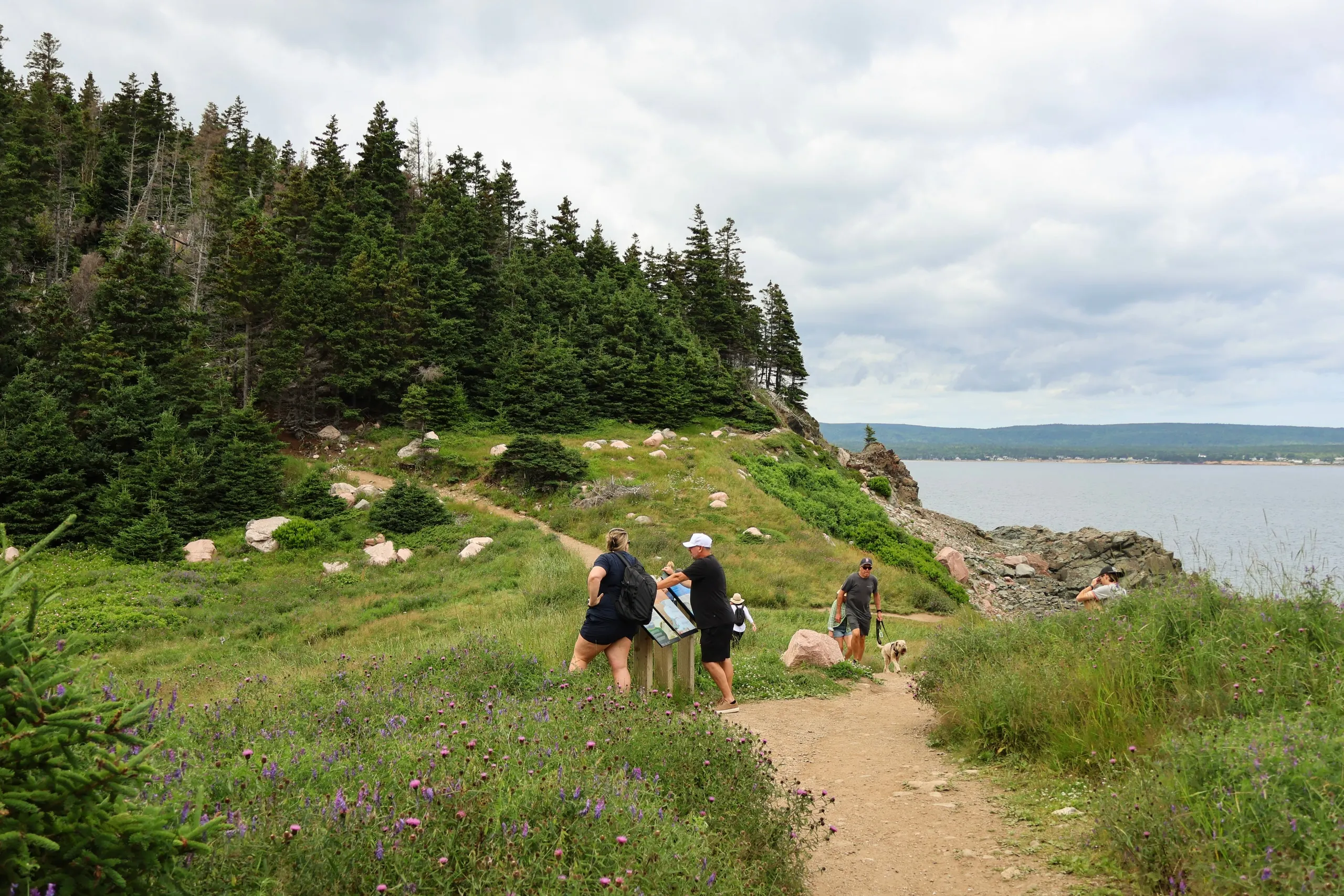 Hikers reading a trail sign on a coastal path above the Atlantic