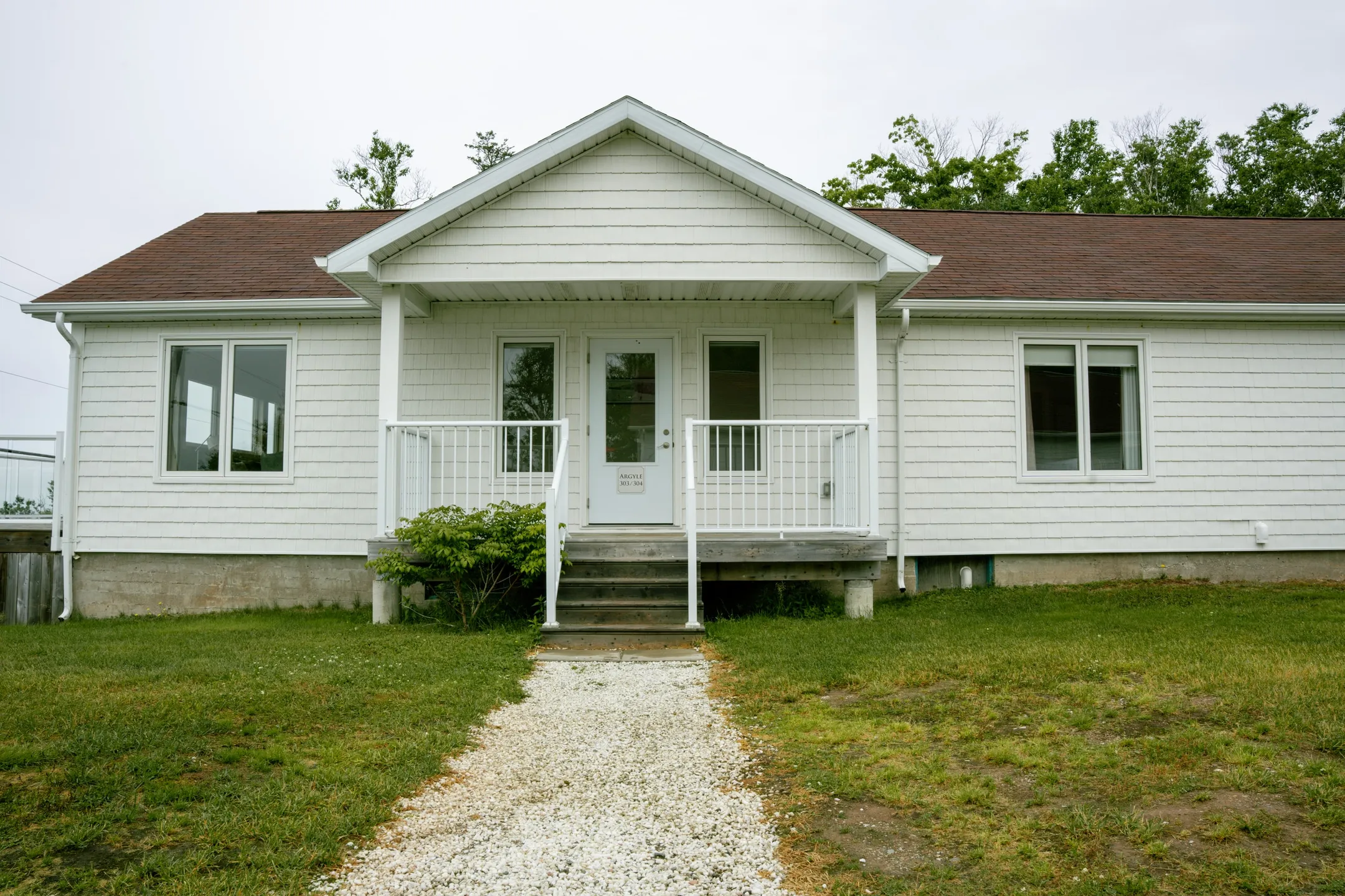 The white exterior of a Courtyard building with a porch and a gravel path leading to the entrance.