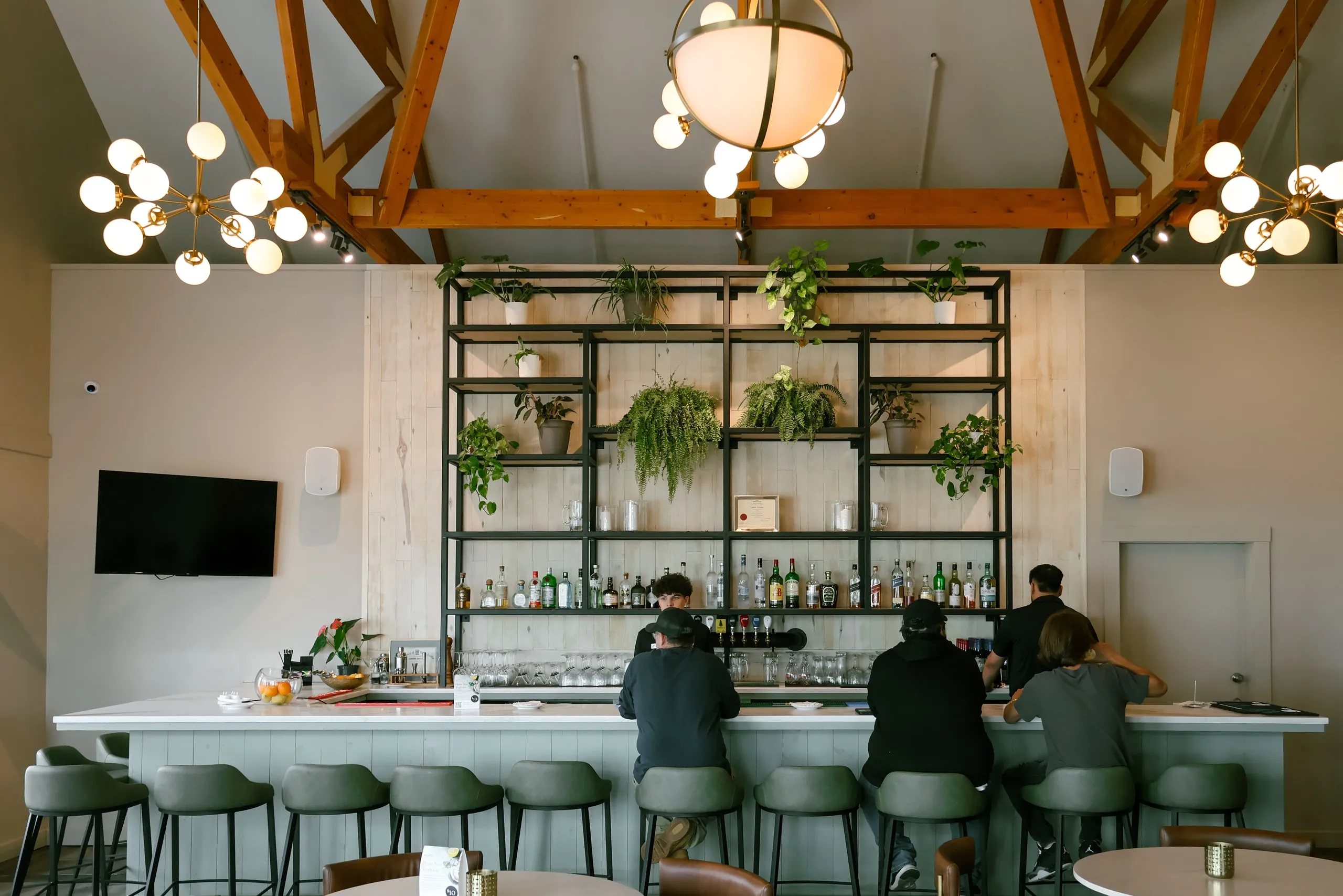 The lounge bar with globe lights, bottle shelves, and guests seated at the counter.