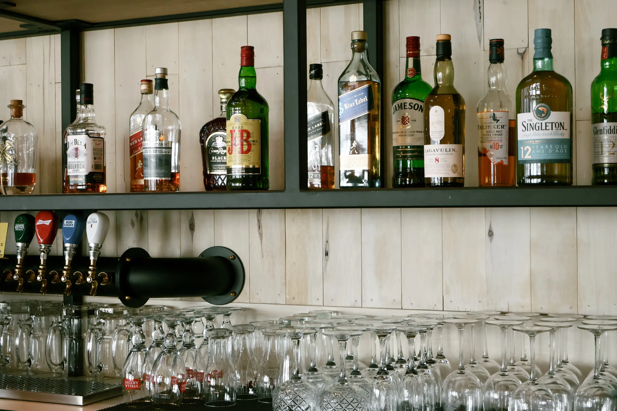 Liquor bottles and stacked glasses behind the bar.