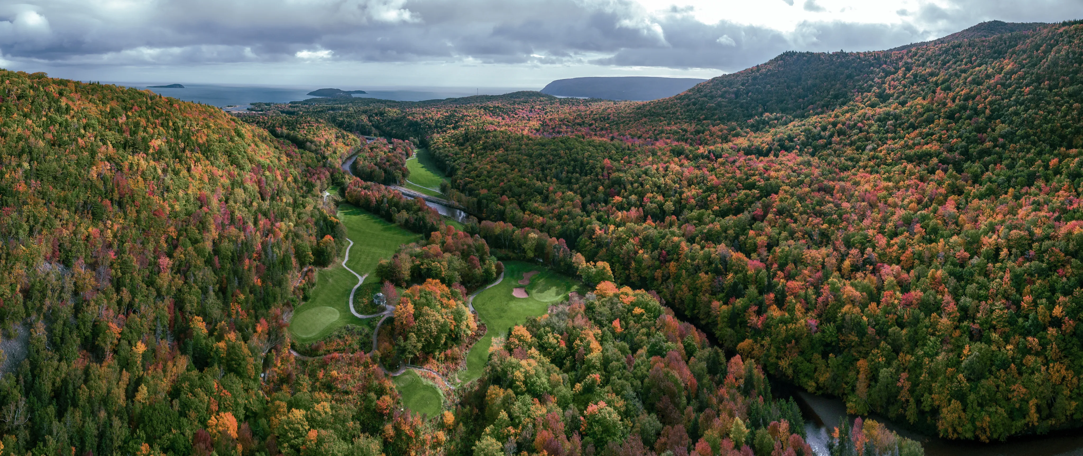Aerial view of Highlands Links in autumn, the fairways winding through red and gold forest.